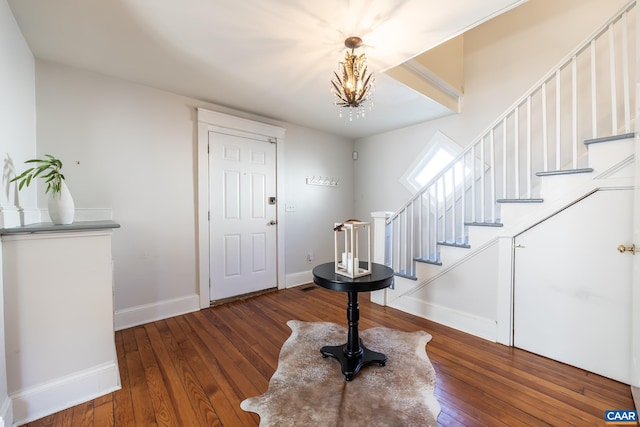 entrance foyer with an inviting chandelier, stairway, baseboards, and hardwood / wood-style floors