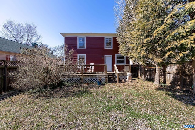 back of property with a fenced backyard, a wooden deck, and a yard