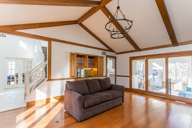 living room with a chandelier, plenty of natural light, beamed ceiling, and wood-type flooring