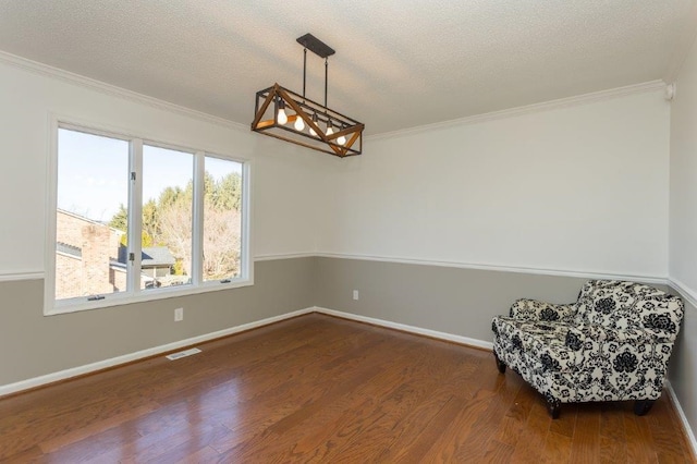 sitting room featuring hardwood / wood-style flooring, ornamental molding, a textured ceiling, and a notable chandelier