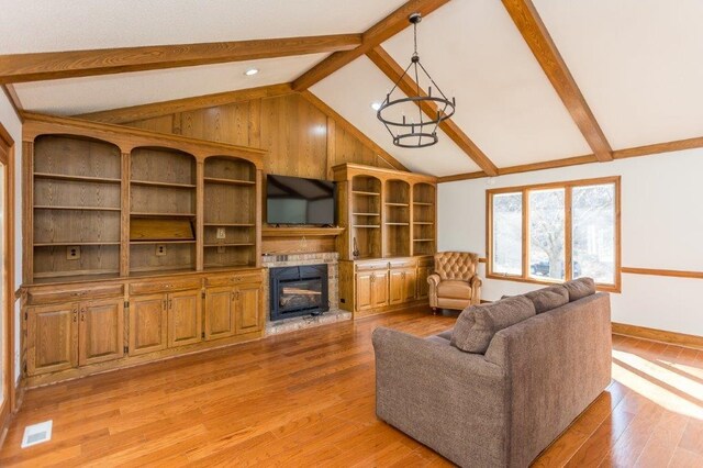 living room featuring vaulted ceiling with beams, a notable chandelier, and light wood-type flooring