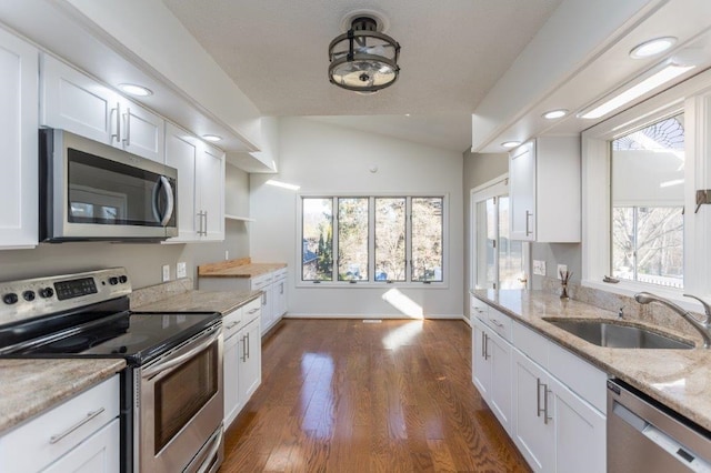 kitchen featuring lofted ceiling, sink, white cabinetry, stainless steel appliances, and light stone countertops