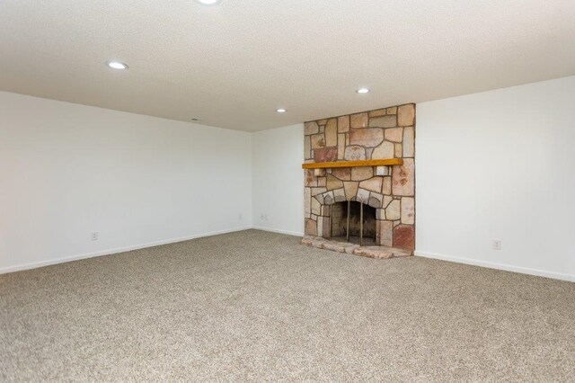 unfurnished living room with a stone fireplace, carpet floors, and a textured ceiling