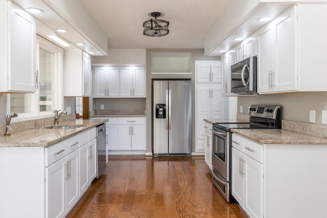 kitchen featuring sink, light stone counters, dark hardwood / wood-style floors, stainless steel appliances, and white cabinets