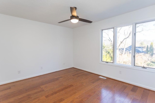 unfurnished room with a wealth of natural light, wood-type flooring, a textured ceiling, and ceiling fan