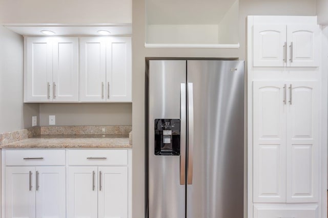 kitchen featuring white cabinetry, stainless steel fridge, and light stone counters