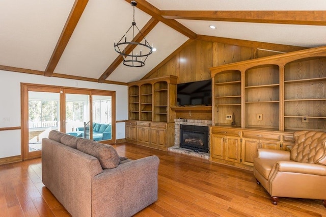 living room with vaulted ceiling with beams, a chandelier, a fireplace, and light wood-type flooring