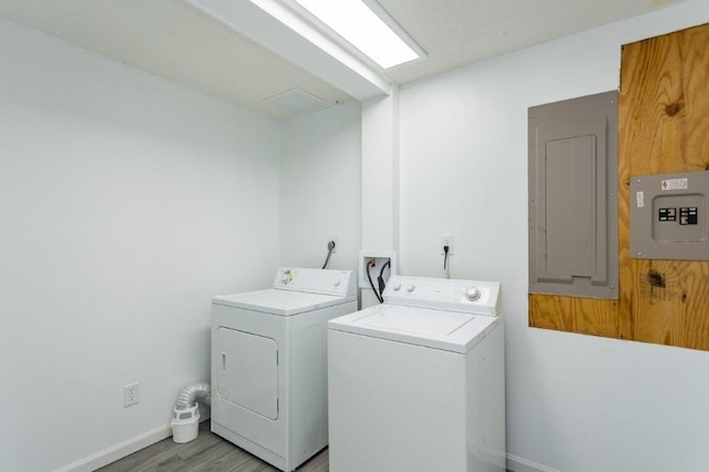 laundry room with electric panel, light hardwood / wood-style floors, and washer and dryer