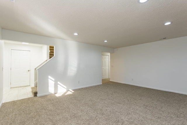 basement featuring light colored carpet and a textured ceiling