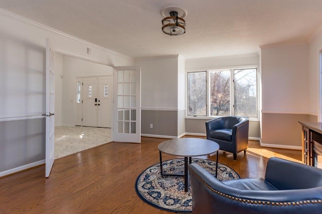 sitting room with crown molding, hardwood / wood-style floors, and a textured ceiling