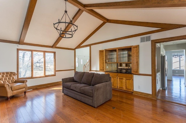 living room featuring lofted ceiling with beams, wood-type flooring, and a notable chandelier