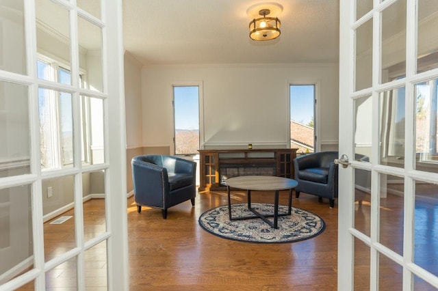 living area featuring french doors, ornamental molding, and hardwood / wood-style flooring