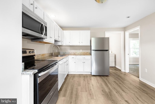 308 Virginia Ave, Mineral, VA 23117 - kitchen with appliances with stainless steel finishes, washer / clothes dryer, white cabinetry, and light wood finished floors