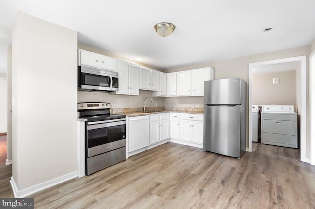 308 Virginia Ave, Mineral, VA 23117 - kitchen with stainless steel appliances, washer and clothes dryer, light wood-style floors, and white cabinetry