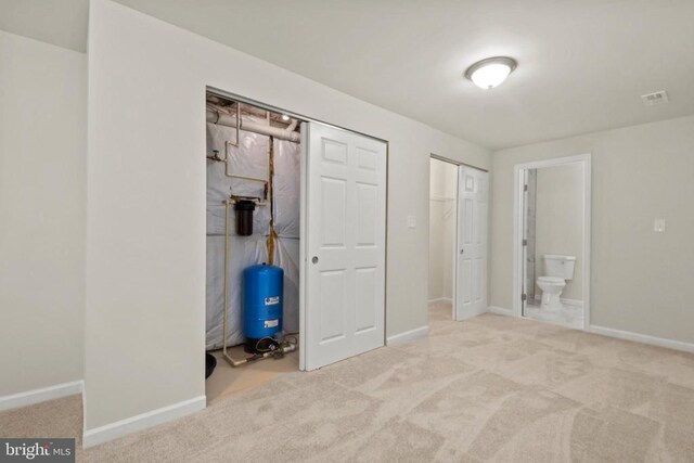 unfurnished bedroom with baseboards, carpet flooring, multiple closets, and ensuite bath