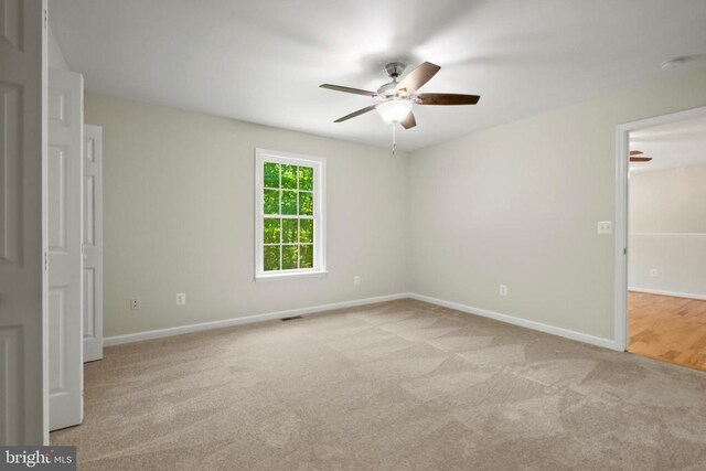 carpeted spare room with a ceiling fan and baseboards