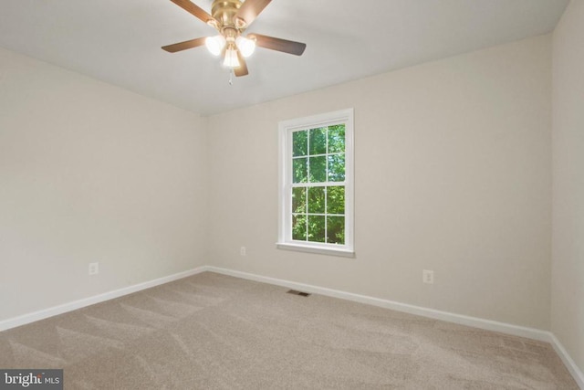 carpeted spare room featuring baseboards and a ceiling fan