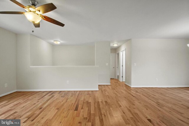 empty room featuring light wood finished floors, baseboards, and a ceiling fan