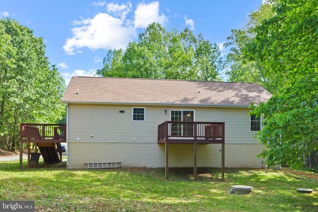 rear view of property featuring a deck, a lawn, and roof with shingles