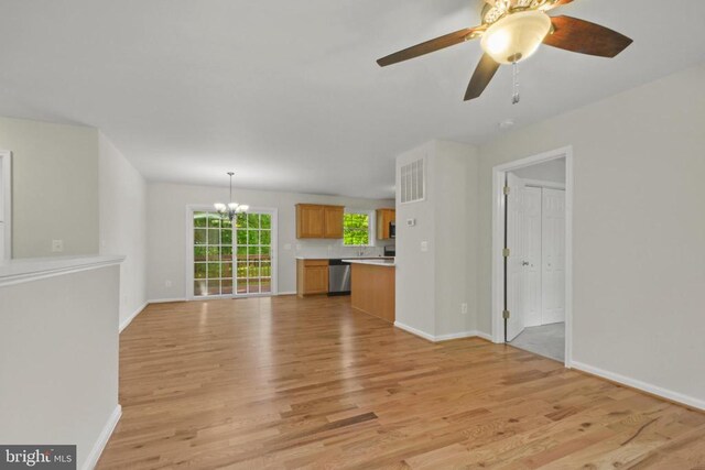 unfurnished living room featuring light wood-type flooring, a chandelier, baseboards, and a ceiling fan
