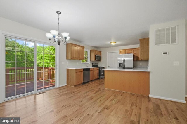 kitchen featuring appliances with stainless steel finishes, a chandelier, light wood-style floors, and light countertops
