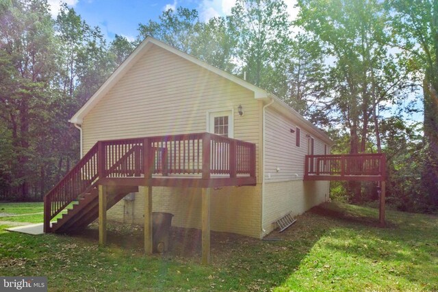 back of property with a deck, stairs, a yard, and brick siding
