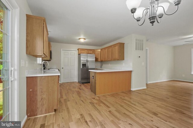 kitchen featuring stainless steel fridge, open floor plan, a sink, light wood-style floors, and a peninsula