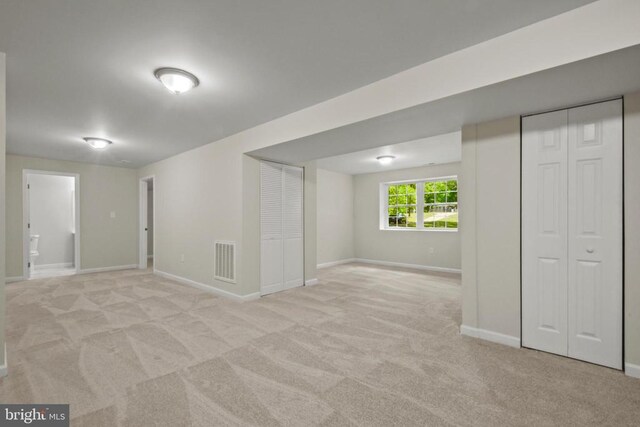 below grade area featuring light colored carpet and baseboards