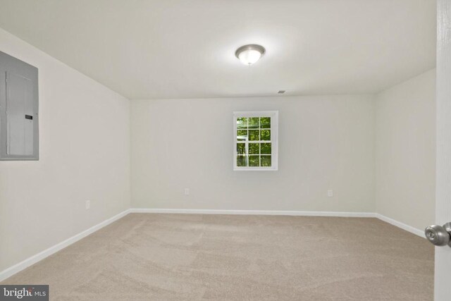 carpeted spare room featuring baseboards and electric panel