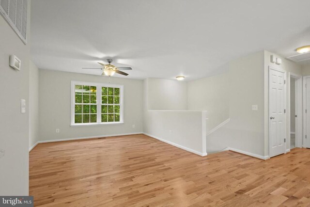 spare room featuring wood finished floors, ceiling fan, and baseboards
