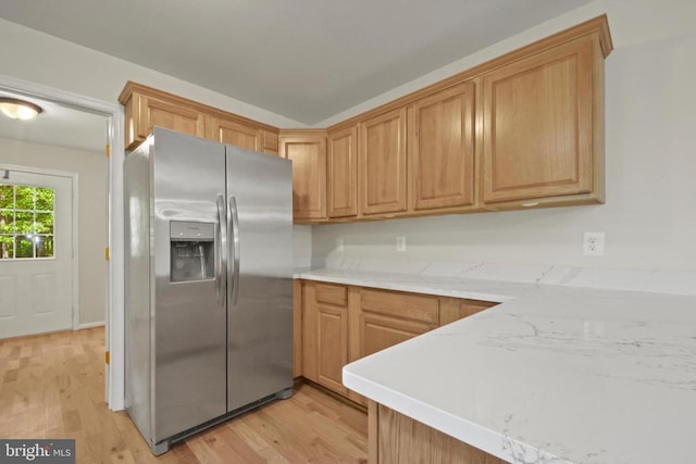 kitchen featuring stainless steel fridge with ice dispenser, light wood-type flooring, and light countertops