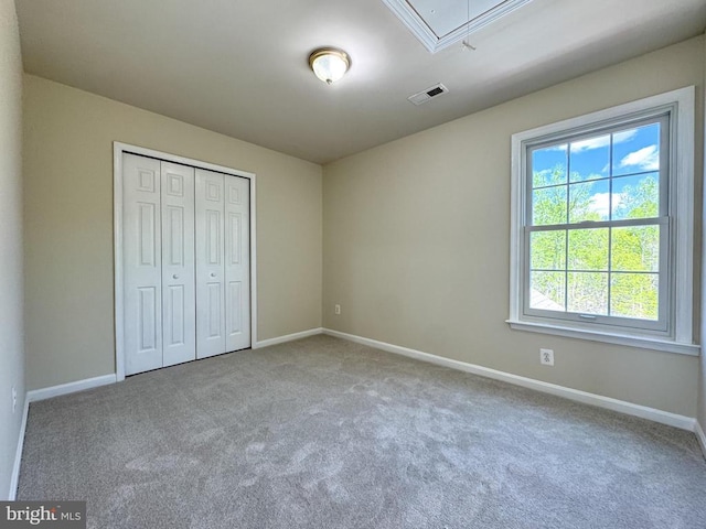 unfurnished bedroom featuring attic access, carpet, and baseboards