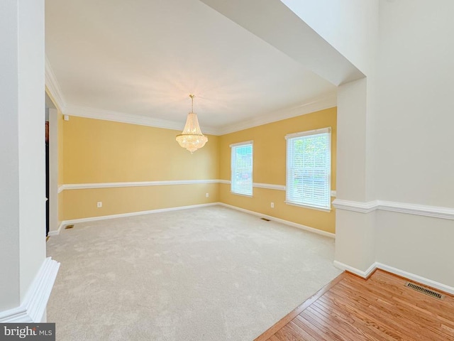 unfurnished room with ornamental molding, a chandelier, baseboards, and wood finished floors