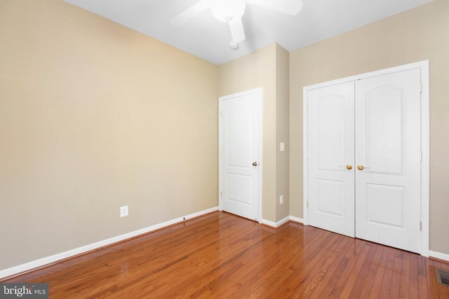 unfurnished bedroom with wood finished floors, baseboards, a closet, and ceiling fan