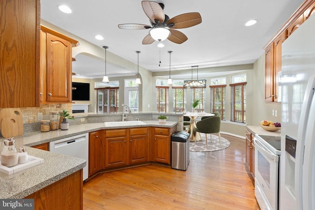 kitchen featuring a sink, white appliances, a peninsula, healthy amount of natural light, and recessed lighting