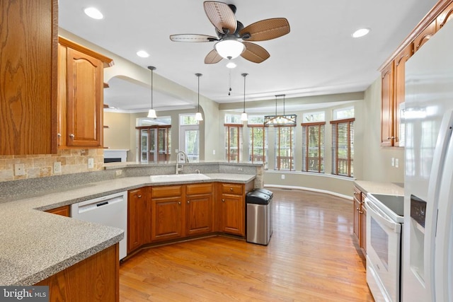 kitchen featuring a sink, white appliances, a peninsula, light wood finished floors, and a ceiling fan