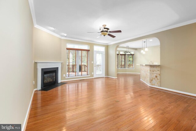 108 Monroe St, Locust Grove, VA 22508 - unfurnished living room featuring light wood finished floors, a fireplace with flush hearth, arched walkways, a ceiling fan, and crown molding