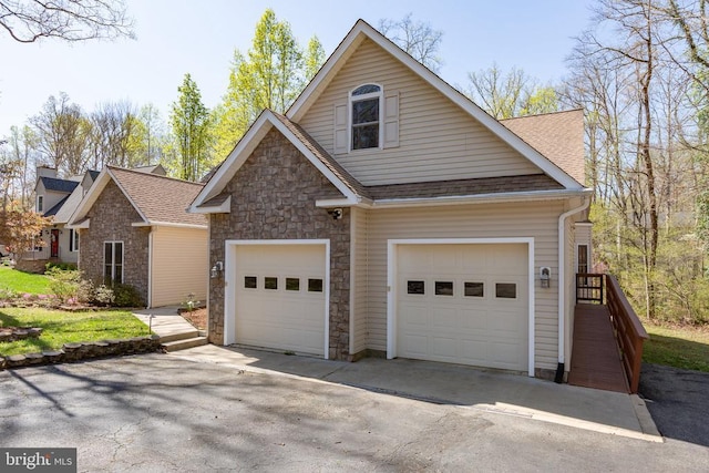 view of front of house with stone siding, roof with shingles, asphalt driveway, and an attached garage