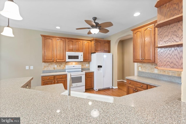 kitchen featuring white appliances, open shelves, arched walkways, a ceiling fan, and backsplash