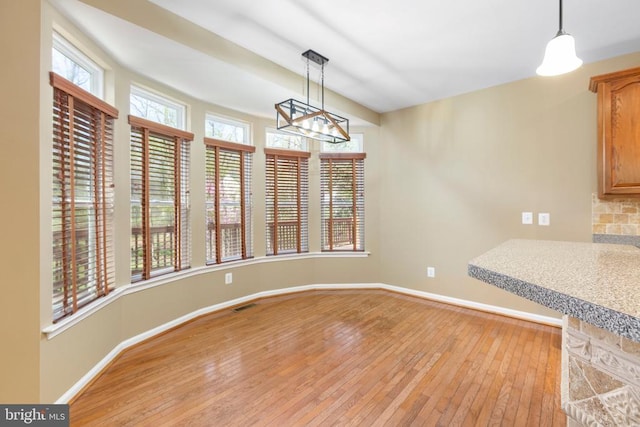 unfurnished dining area with light wood finished floors, baseboards, and a chandelier