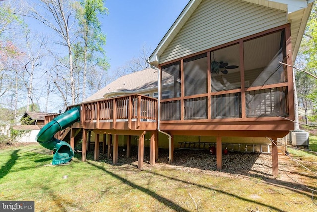 rear view of house with a sunroom, a yard, a playground, and cooling unit