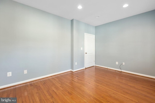 spare room with baseboards, wood finished floors, and recessed lighting