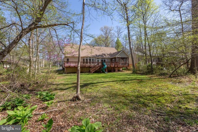 view of green lawn with a wooden deck and stairway