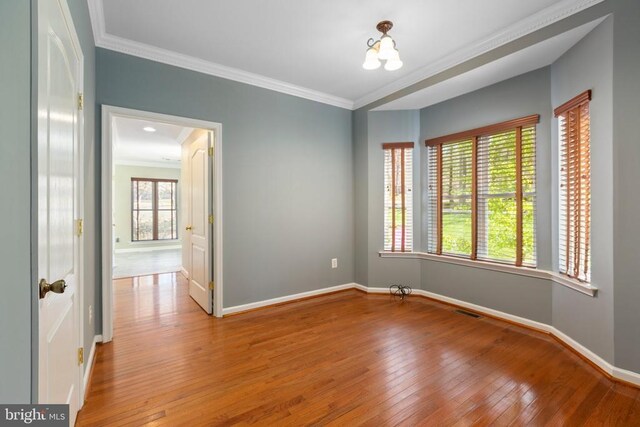 unfurnished room featuring ornamental molding, baseboards, and hardwood / wood-style floors