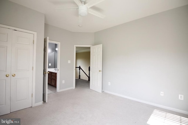 - unfurnished bedroom featuring light carpet, a closet, ceiling fan, and ensuite bathroom