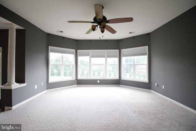  - empty room featuring ornate columns, healthy amount of natural light, ceiling fan, and carpet floors