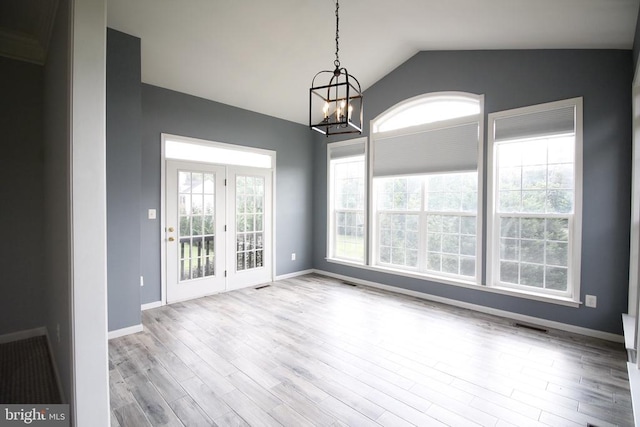  - unfurnished dining area with a chandelier, wood finished floors, and vaulted ceiling