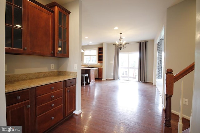  - kitchen featuring a chandelier, dark wood-style flooring, glass insert cabinets, light stone countertops, and recessed lighting