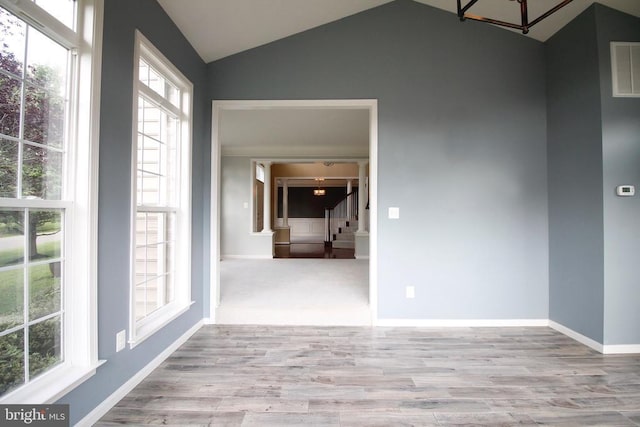  - unfurnished room with lofted ceiling, wood finished floors, stairway, and healthy amount of natural light