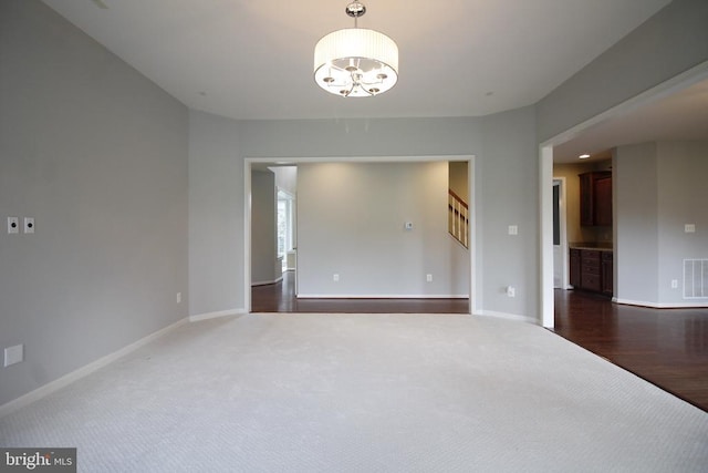  - empty room featuring dark carpet, a chandelier, and stairs